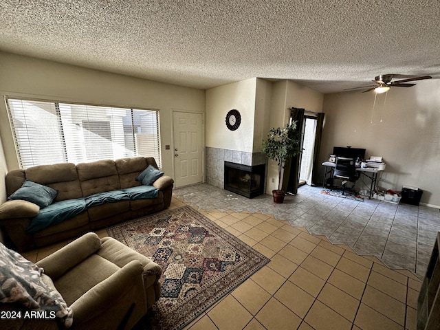 tiled living room featuring ceiling fan, a fireplace, a healthy amount of sunlight, and a textured ceiling