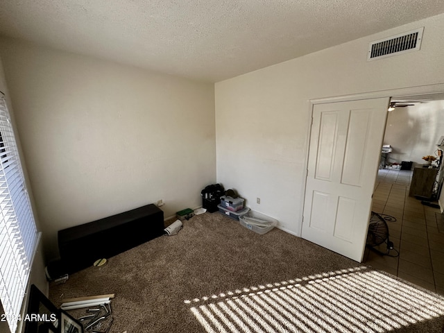 misc room featuring dark colored carpet, ceiling fan, and a textured ceiling