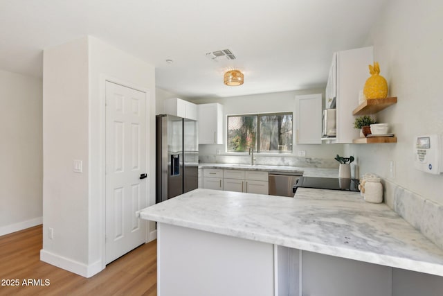 7500 E Deer Valley Rd Unit 132, Scottsdale, AZ 85255 - kitchen featuring appliances with stainless steel finishes, light wood finished floors, a peninsula, light stone counters, and a sink