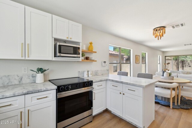 7500 E Deer Valley Rd Unit 132, Scottsdale, AZ 85255 - kitchen featuring stainless steel appliances, healthy amount of natural light, a peninsula, and white cabinetry