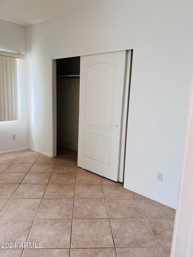 unfurnished bedroom with a closet and light tile patterned floors