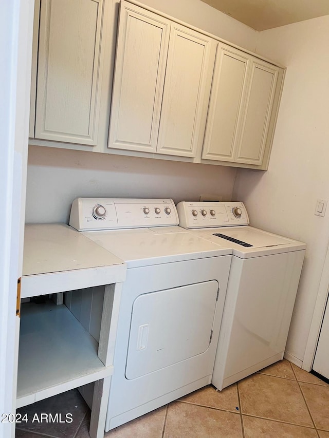 laundry room featuring light tile patterned flooring, washing machine and dryer, and cabinets