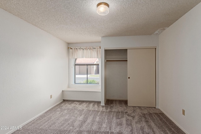 unfurnished bedroom with carpet, a textured ceiling, baseboards, and a closet