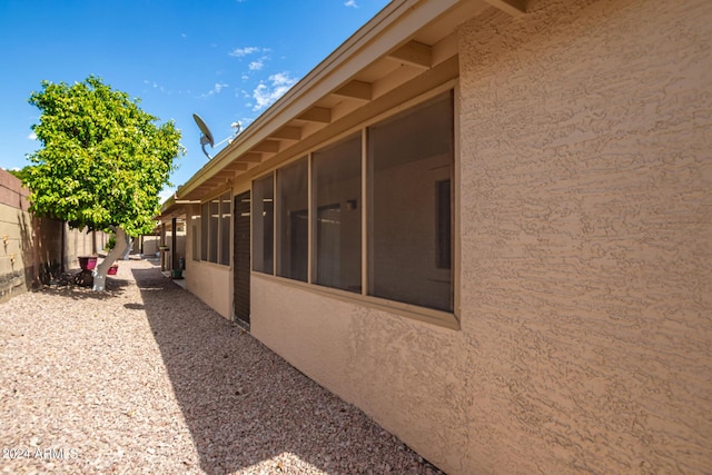 view of home's exterior featuring fence, a sunroom, and stucco siding