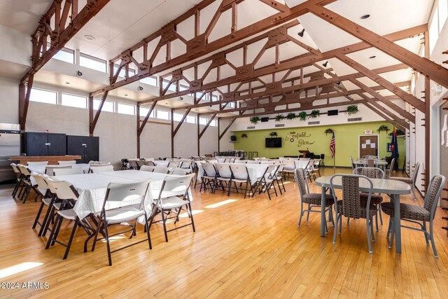 dining space with a towering ceiling and hardwood / wood-style flooring