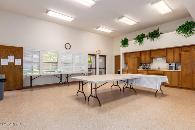 recreation room with light floors, baseboards, high vaulted ceiling, and a sink