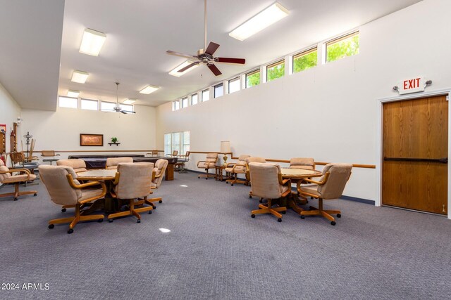 carpeted dining room featuring a healthy amount of sunlight, ceiling fan, and a towering ceiling