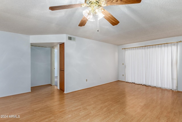 spare room featuring baseboards, visible vents, a ceiling fan, a textured ceiling, and light wood-type flooring