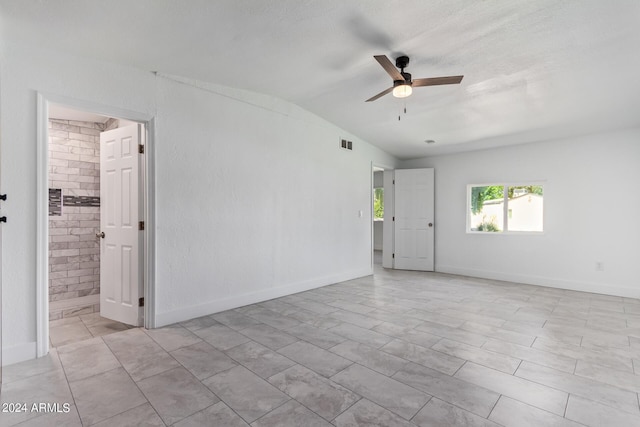 spare room featuring vaulted ceiling, ceiling fan, and brick wall