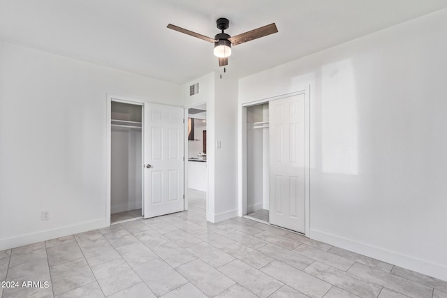 unfurnished bedroom with ceiling fan and two closets