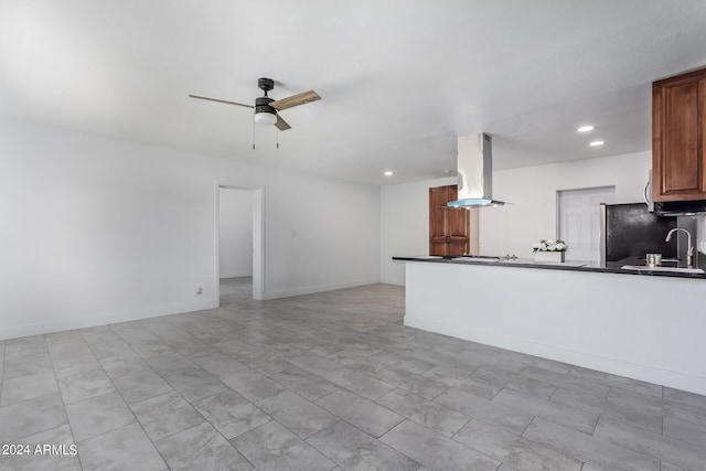 kitchen featuring ceiling fan, sink, island exhaust hood, kitchen peninsula, and black refrigerator