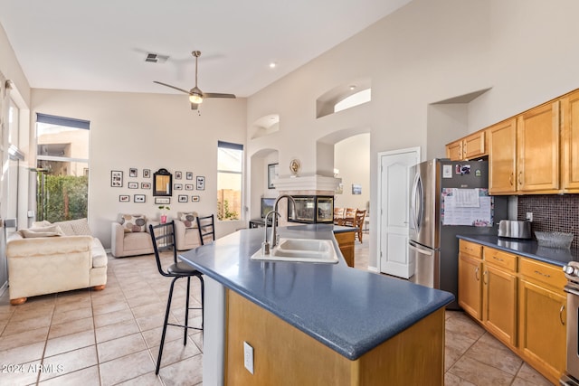 kitchen with a kitchen bar, backsplash, ceiling fan, sink, and an island with sink