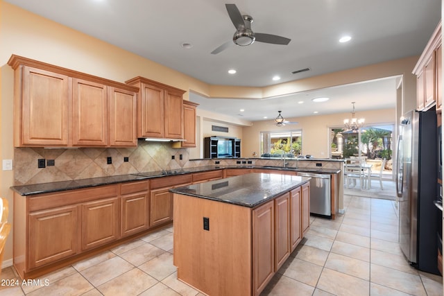 kitchen with a center island, tasteful backsplash, appliances with stainless steel finishes, a sink, and a peninsula