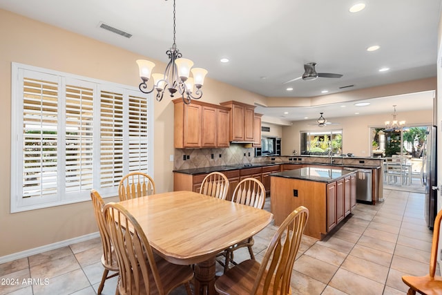 tiled dining room featuring ceiling fan with notable chandelier and sink