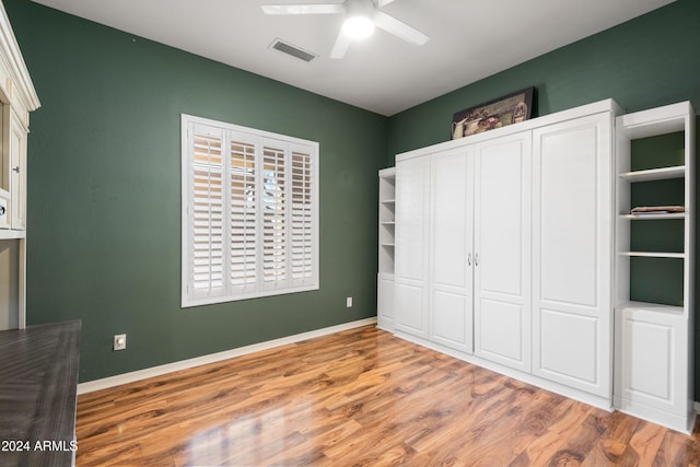 unfurnished bedroom with ceiling fan, wood finished floors, visible vents, and baseboards