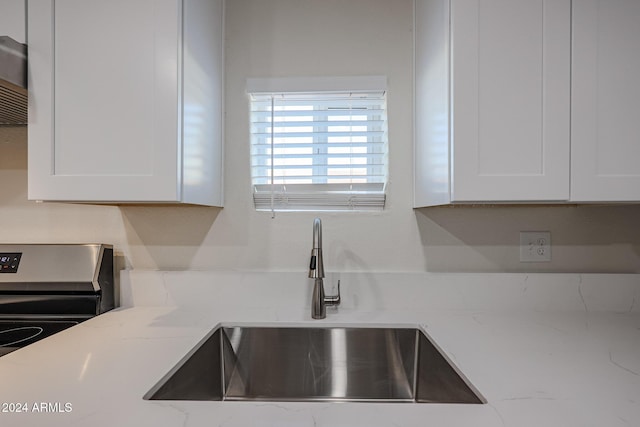 kitchen with white cabinetry, light stone countertops, sink, and stainless steel electric stove