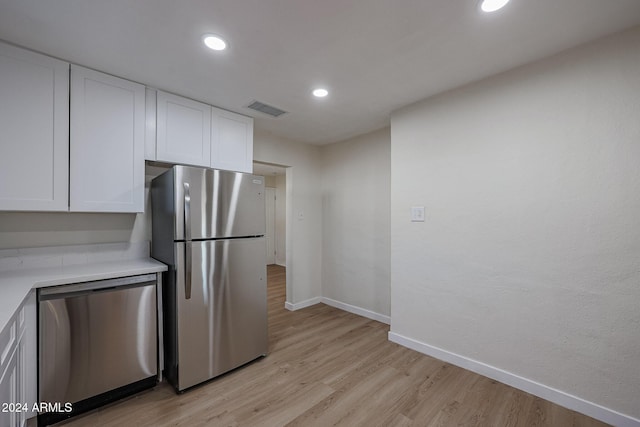 kitchen with white cabinets, appliances with stainless steel finishes, and light hardwood / wood-style flooring