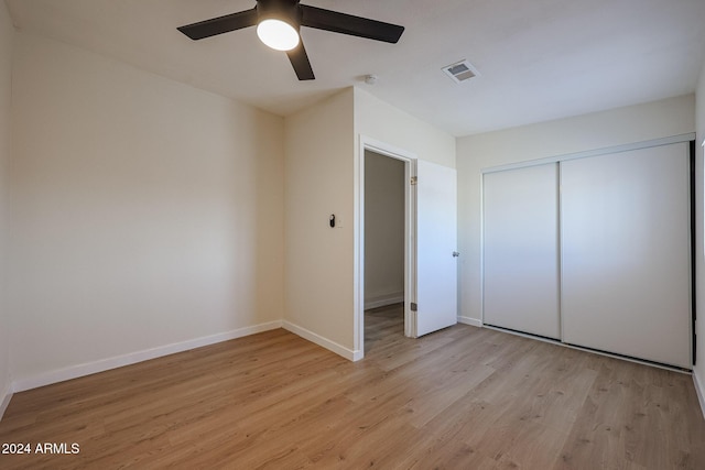 unfurnished bedroom featuring ceiling fan, a closet, and light wood-type flooring