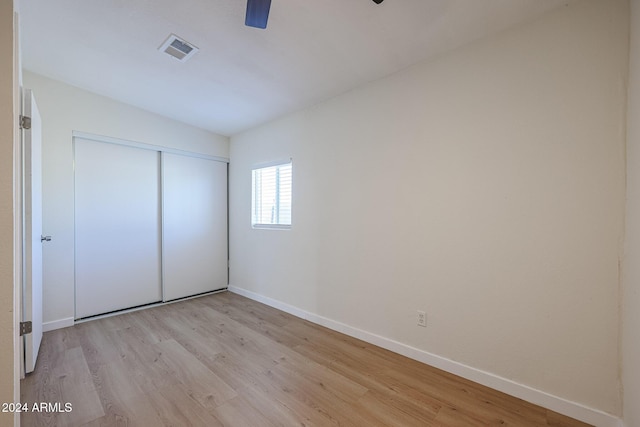 unfurnished bedroom featuring ceiling fan, light wood-type flooring, and a closet