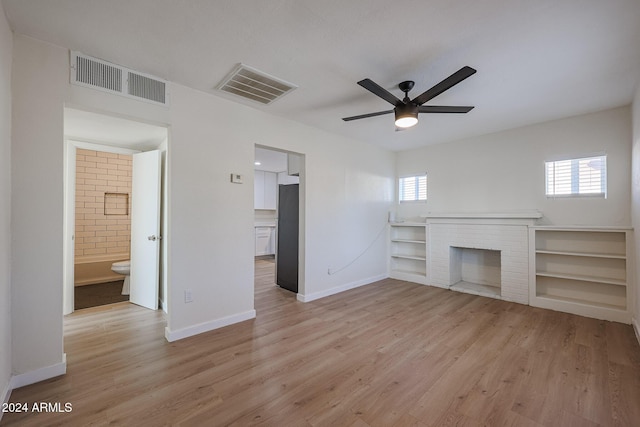 unfurnished living room with plenty of natural light, ceiling fan, light wood-type flooring, and a fireplace