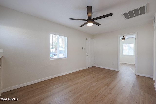 empty room with ceiling fan, a healthy amount of sunlight, and light hardwood / wood-style floors