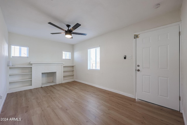 unfurnished living room featuring a brick fireplace, ceiling fan, plenty of natural light, and light hardwood / wood-style flooring