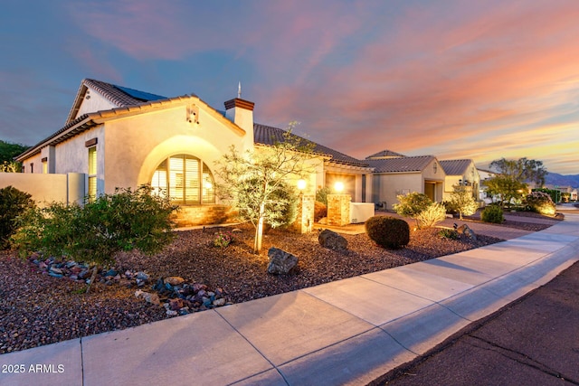18322 W Thistle Landing Dr, Goodyear, AZ 85338 - mediterranean / spanish home featuring a tile roof, solar panels, stucco siding, and a chimney