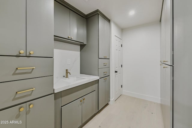 washroom with a sink, light wood-type flooring, and baseboards