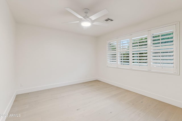 spare room featuring light wood finished floors, visible vents, baseboards, and a ceiling fan