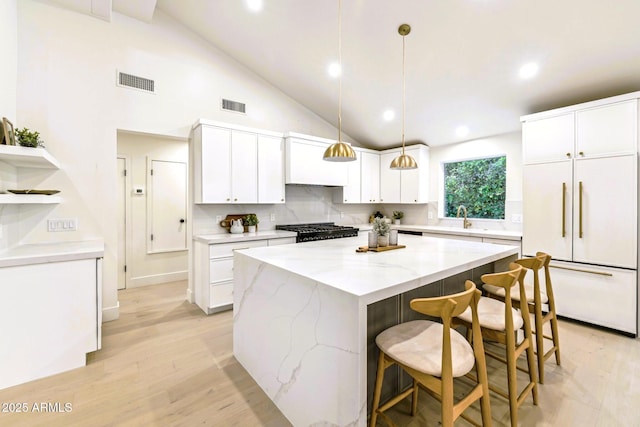 kitchen with stove, visible vents, built in refrigerator, and a center island