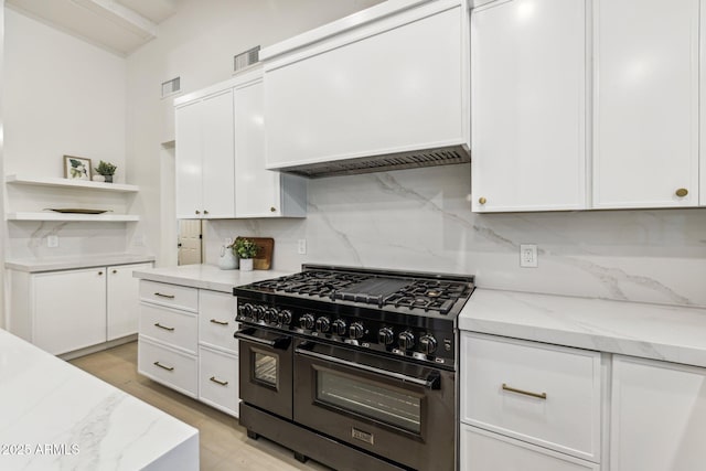 kitchen with tasteful backsplash, visible vents, range with two ovens, light stone counters, and white cabinets