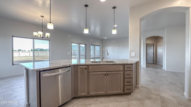 kitchen with pendant lighting, dishwasher, a center island with sink, sink, and light stone counters