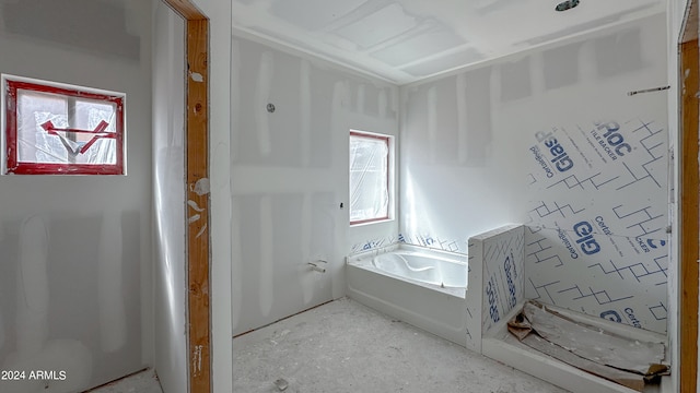 bathroom with concrete flooring and a tub