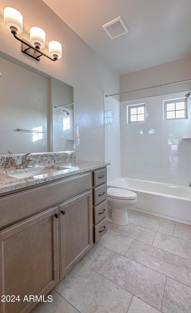 full bathroom featuring vanity, tiled shower / bath combo, and toilet