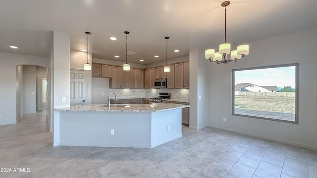 kitchen featuring light stone countertops, sink, hanging light fixtures, an inviting chandelier, and appliances with stainless steel finishes