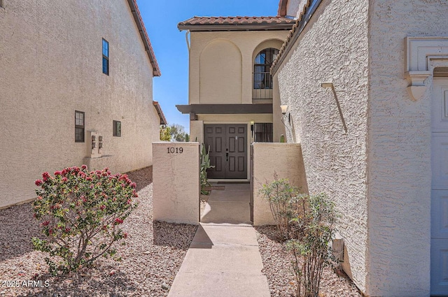 property entrance featuring a tile roof and stucco siding