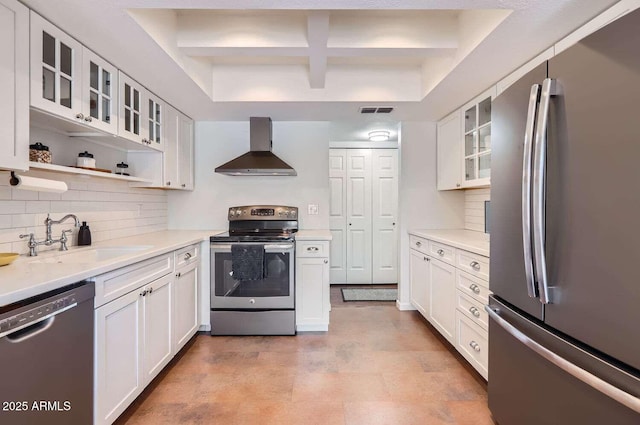 kitchen featuring visible vents, appliances with stainless steel finishes, white cabinetry, a sink, and wall chimney exhaust hood