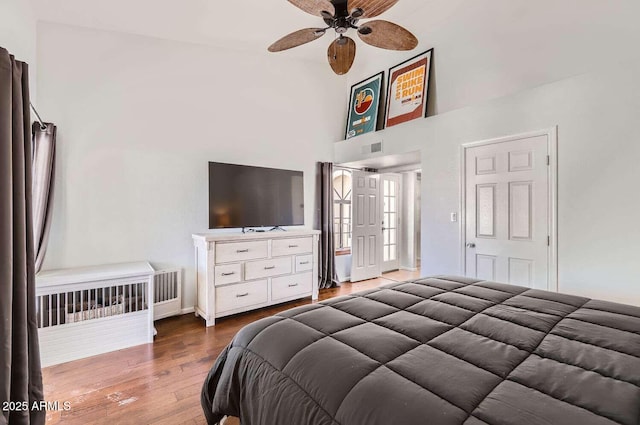 bedroom featuring ceiling fan, a towering ceiling, and wood finished floors