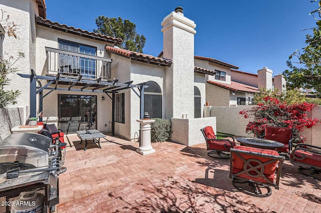 view of patio / terrace featuring a balcony, fence, and a fire pit