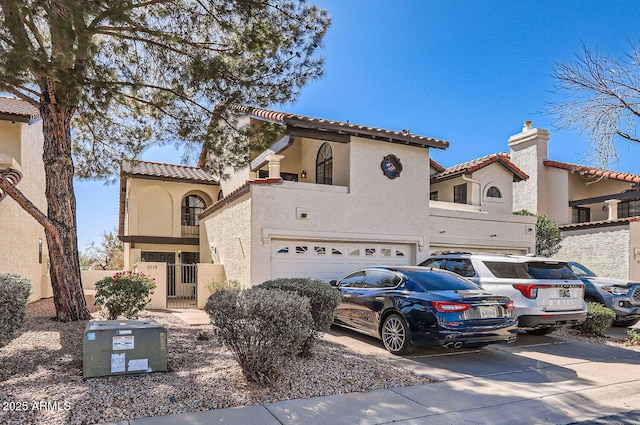 mediterranean / spanish house with a tile roof, driveway, an attached garage, and stucco siding