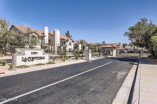 view of road with a gated entry, a residential view, a gate, and curbs