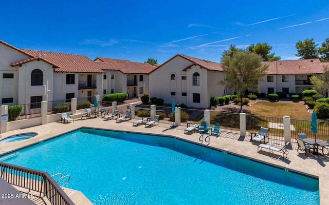 community pool featuring a patio area, a hot tub, and fence