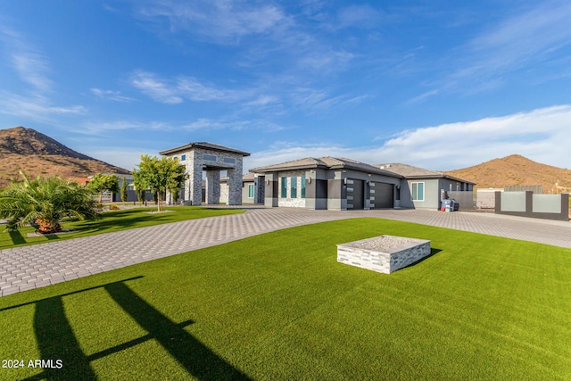 back of property with fence, a garage, decorative driveway, a lawn, and a mountain view