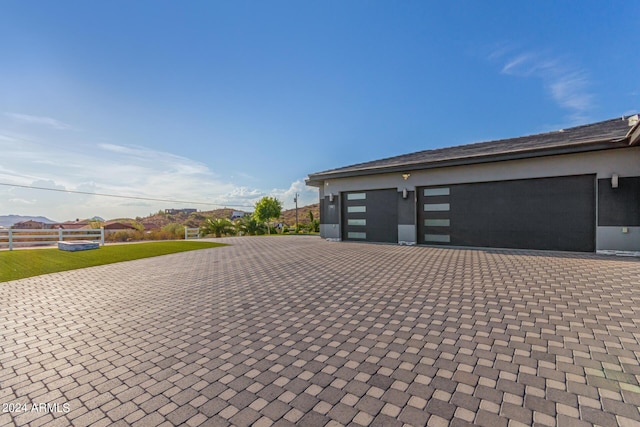 garage with decorative driveway and fence