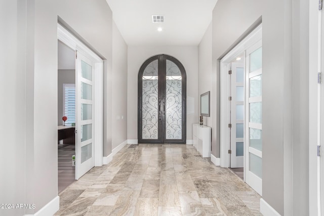 foyer with baseboards, french doors, visible vents, and arched walkways