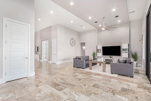 tiled living room featuring ceiling fan and a towering ceiling