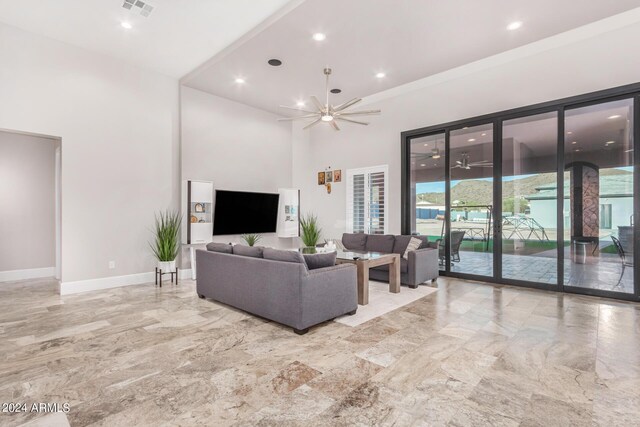 living room featuring a high ceiling, ceiling fan, and tile patterned floors