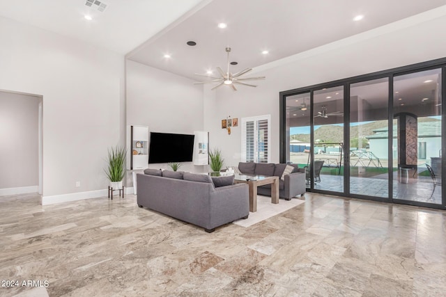 living area with a high ceiling, visible vents, marble finish floor, and baseboards