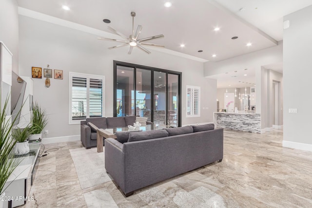 living area with baseboards, marble finish floor, and a towering ceiling