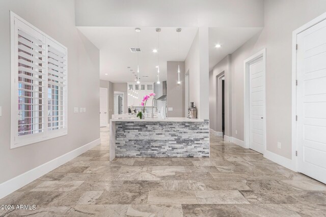 kitchen with light tile patterned floors, pendant lighting, and wall chimney exhaust hood